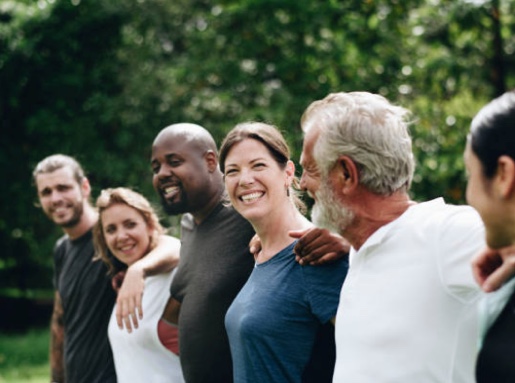 A group of adults outside smile at each other