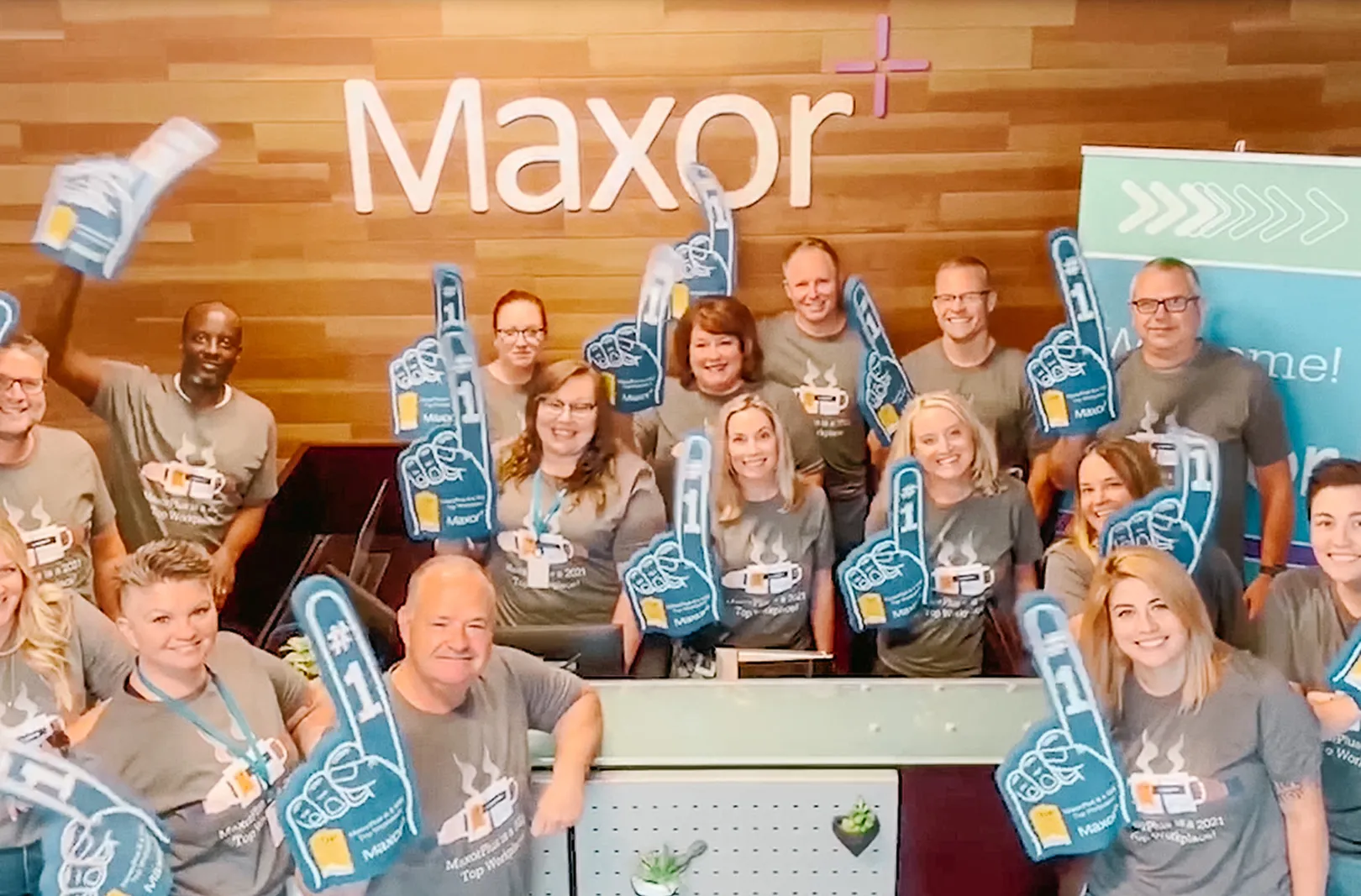 Maxor team celebrating in front of Maxor interior sign.
